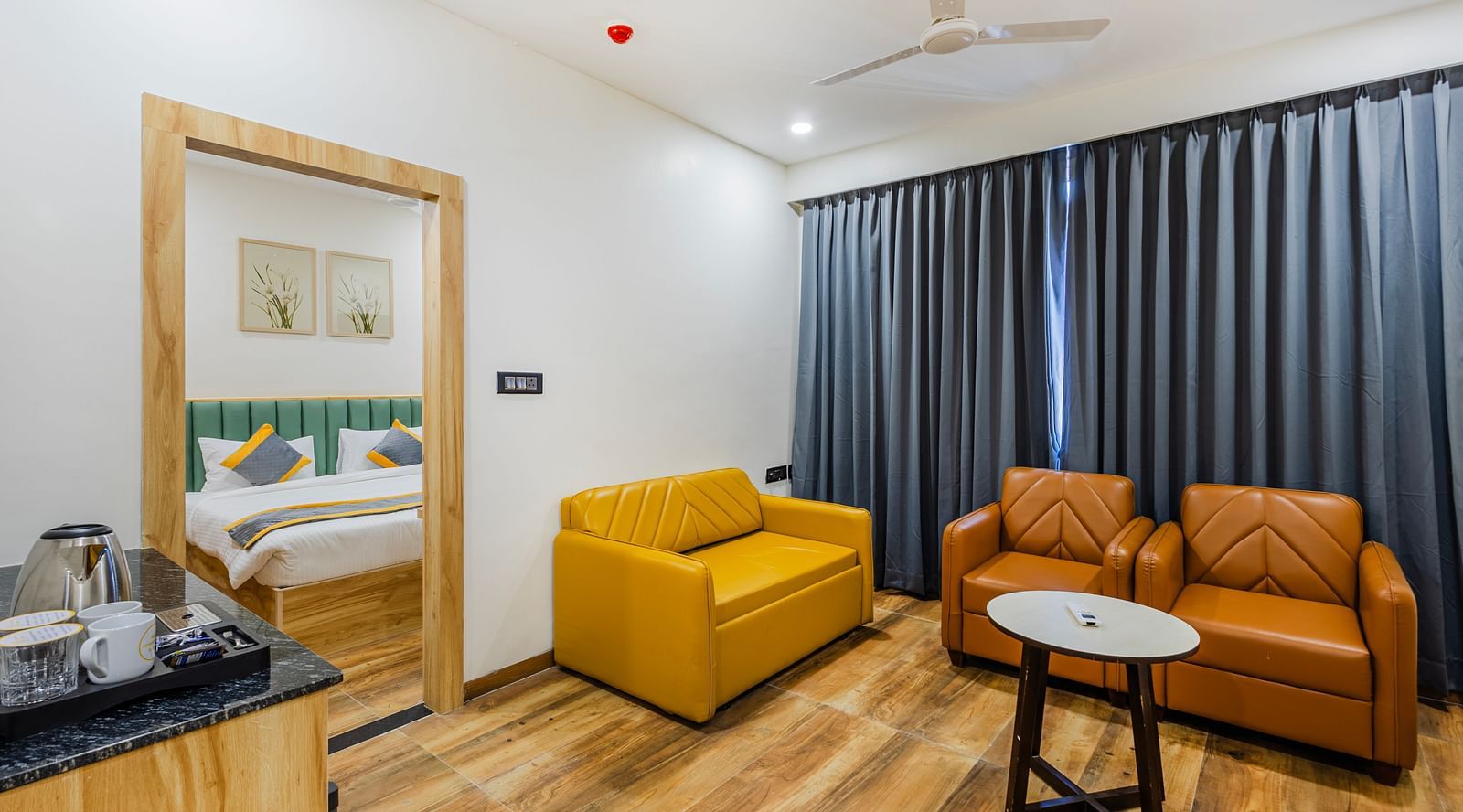 Lemonridge Hotels, KPHB | Hotel room with a seating area, including a yellow sofa and armchairs. Relaxing space.